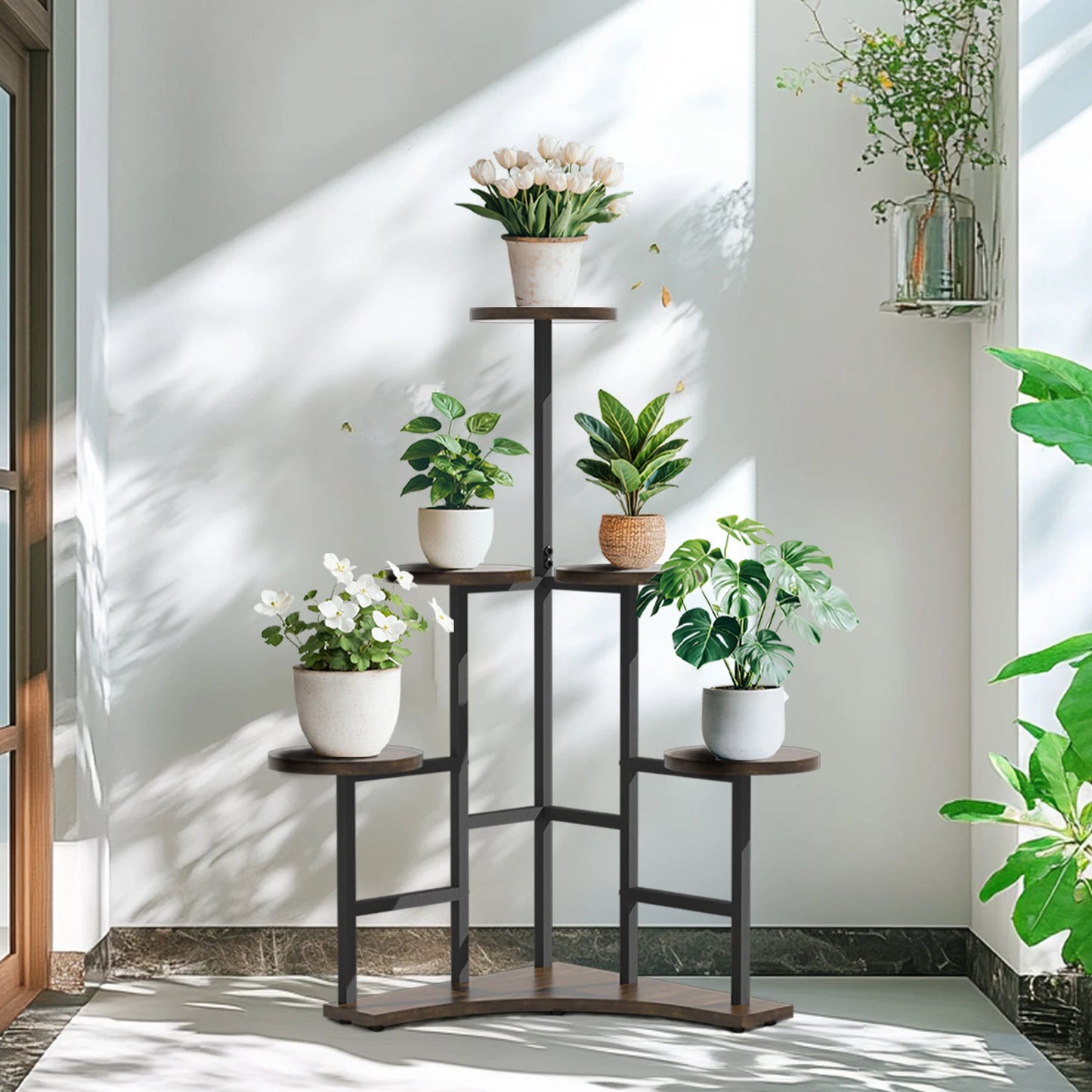 Decorative plant stand with various potted plants against a white wall.