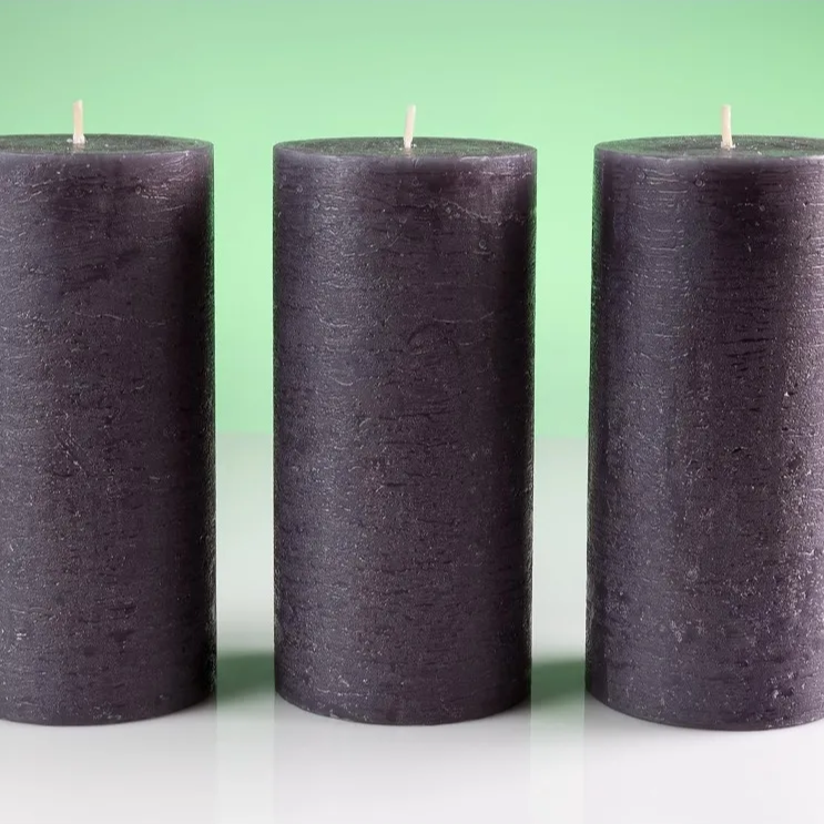 Three black candles on a white surface with a green background