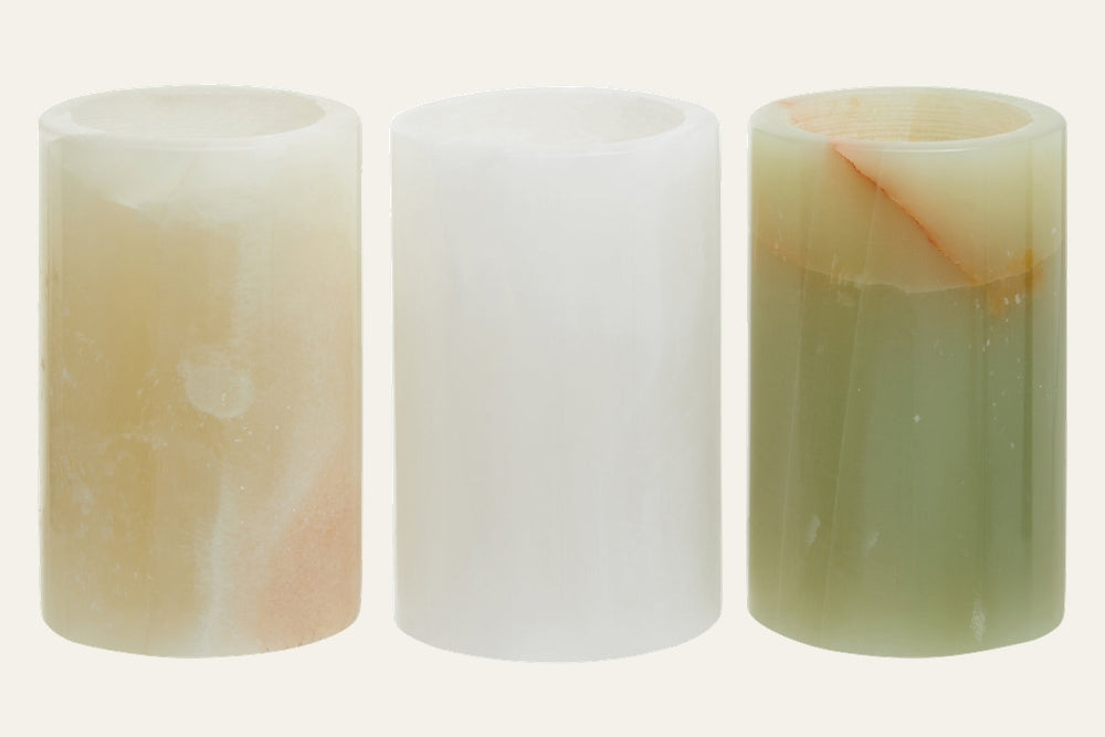 Aevella Onyx Tealight Holder Set: three polished cylindrical onyx tealight holders in cream, white, and olive green with natural banding and a translucent finish