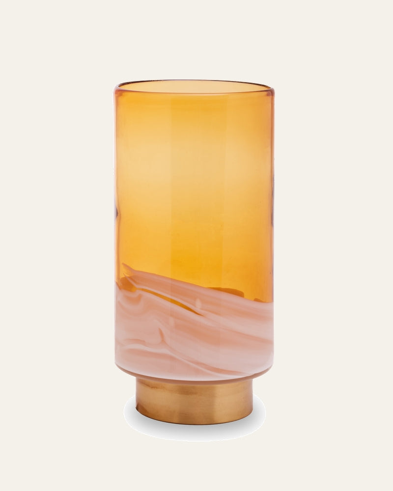 Amalia Amber Glass Vase — tall cylindrical amber glass with a white marbled swirl near the bottom and a round brass-finish pedestal base.