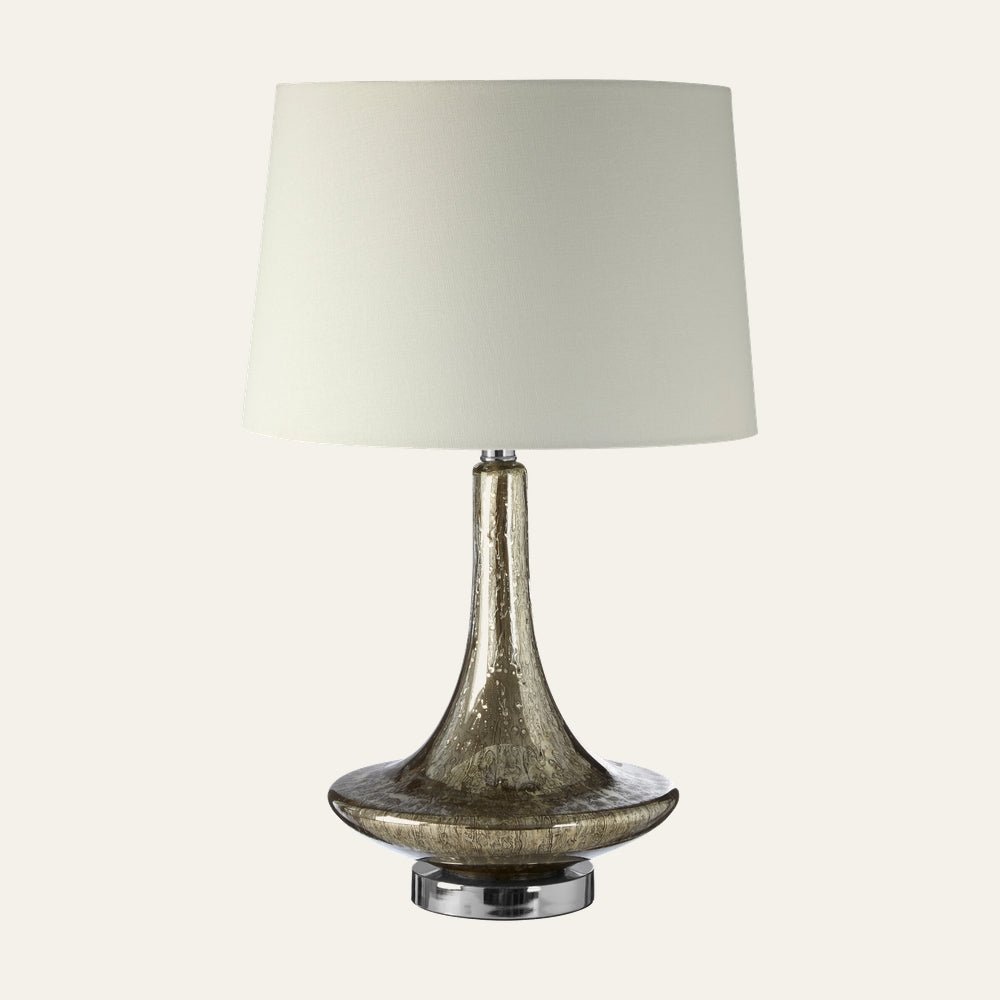 Amayana Glass Table Lamp with amber-brown bubbled glass flared base, chrome circular pedestal, and white tapered fabric drum shade