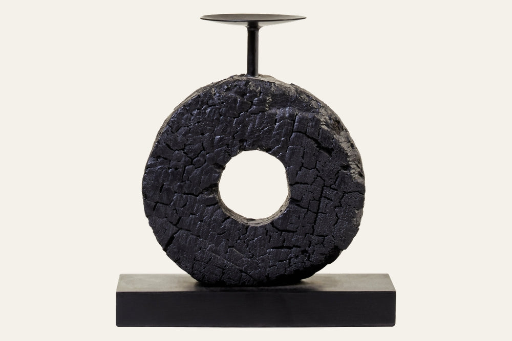 Arden Wood Log Candle Holder – charred, cracked wood ring with central hole mounted on a rectangular black base and topped with a slim metal candle plate