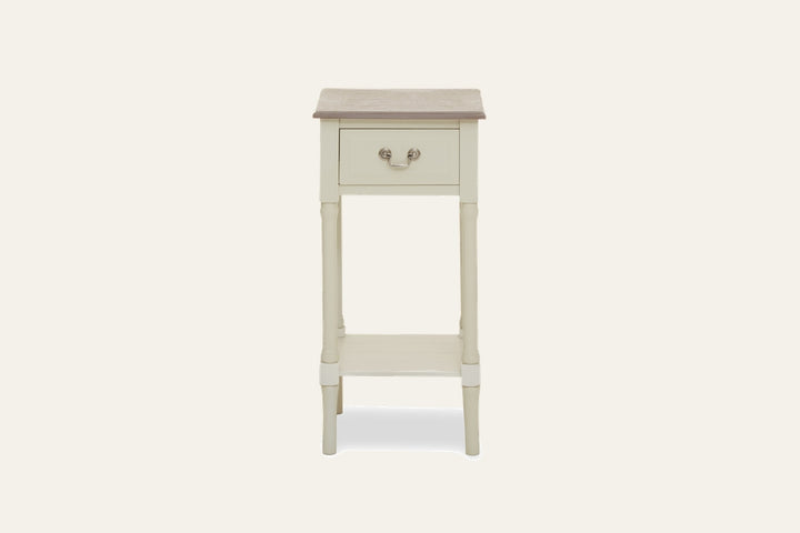 Arlen Ivory Wood Side Table — slim ivory-painted wood side table with contrasting light brown wood top, single front drawer with metal bail pull, turned legs and lower shelf