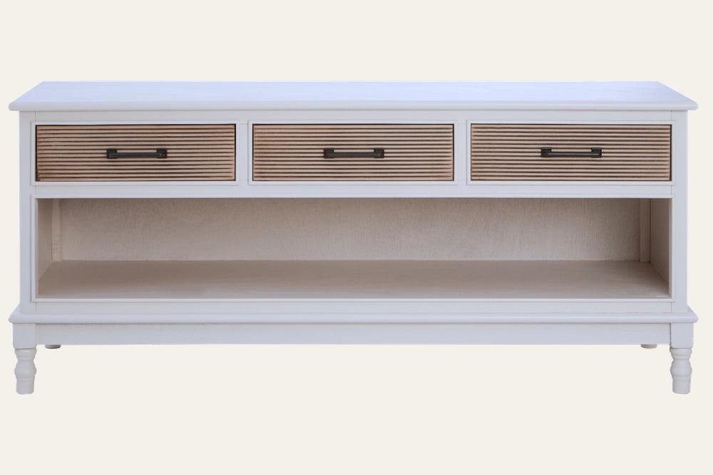 Arlen Three Drawer Cabinet with white painted wood frame, three natural slatted drawer fronts with black metal handles, open lower shelf and turned legs