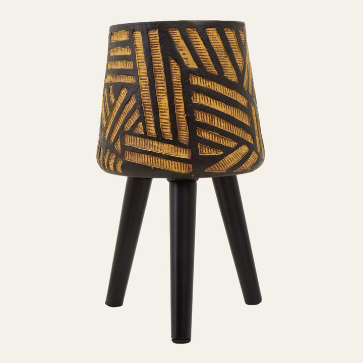 Arric Angular Leg Planter — textured dark pot with carved yellow‑gold geometric pattern mounted on three matte black angled legs.