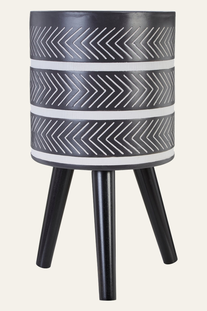 Arric Planter — cylindrical black planter with carved white chevron stripes and horizontal bands, mounted on three tapered black legs