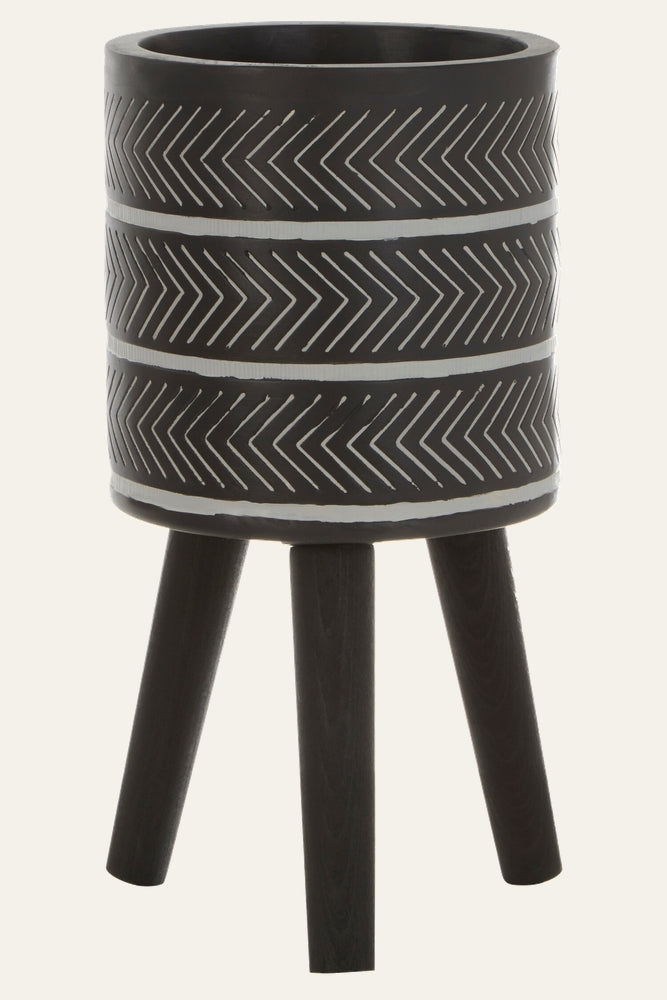 Arric Planter: matte black cylindrical planter on three dark wood tripod legs with white chevron stripe pattern around the bowl