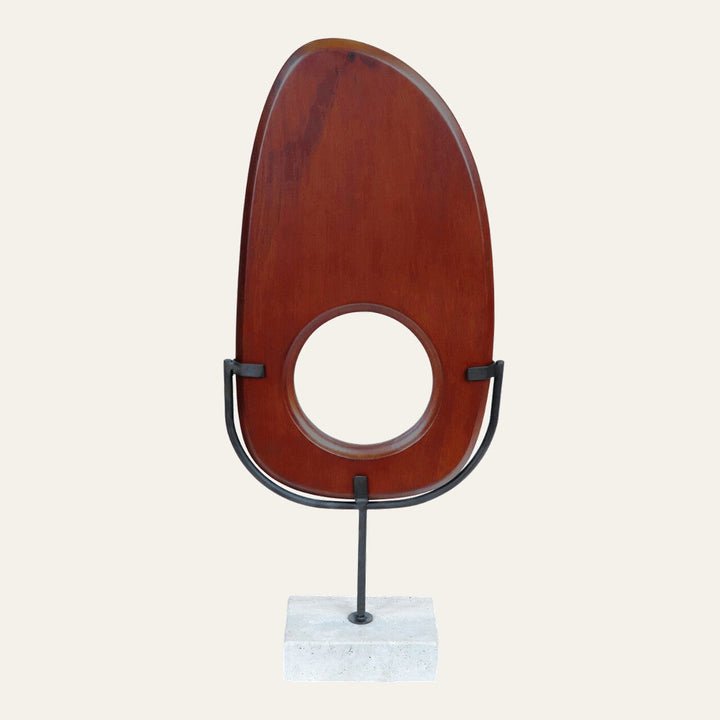 Arsen Wood Vertical Sculpture: elongated reddish-brown wooden panel with a central round cutout, mounted in a black metal U-stand on a rectangular concrete base.