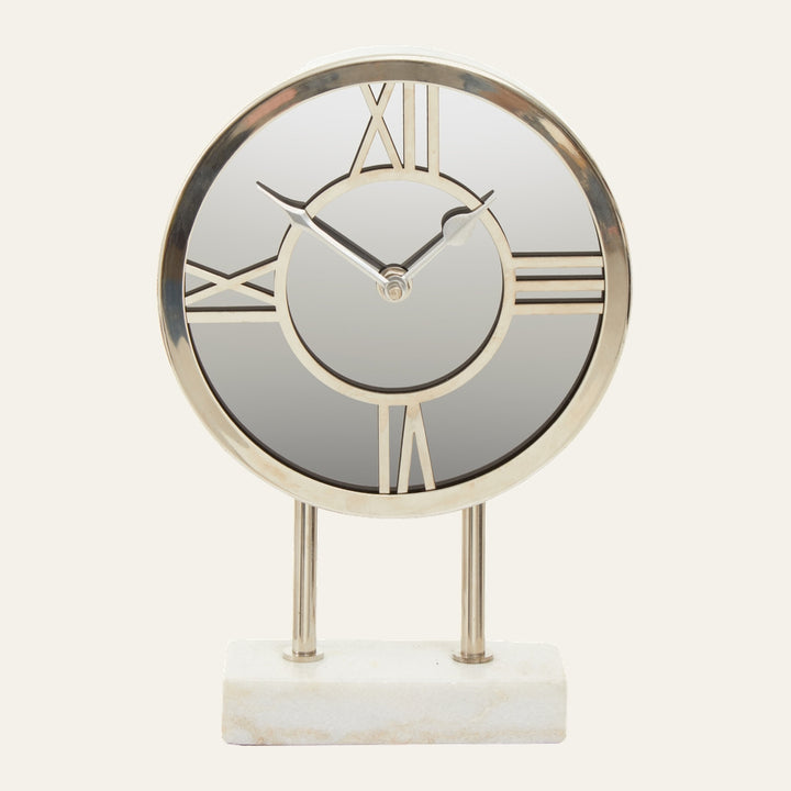 Artor Marble Clock — round mirrored face with gold-tone metal frame and Roman numerals, slender gold hands, supported by two gold rods on a white marble rectangular base