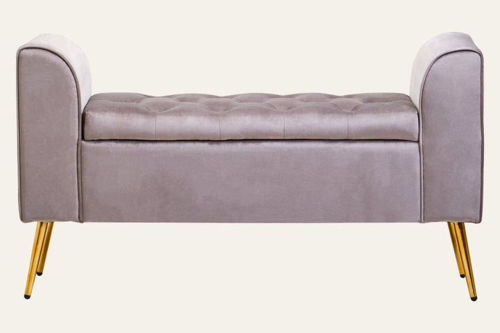 Caelis Mink Velvet Storage Bench with tufted top, mink velvet upholstery, curved armrests on both ends, and gold tapered metal legs