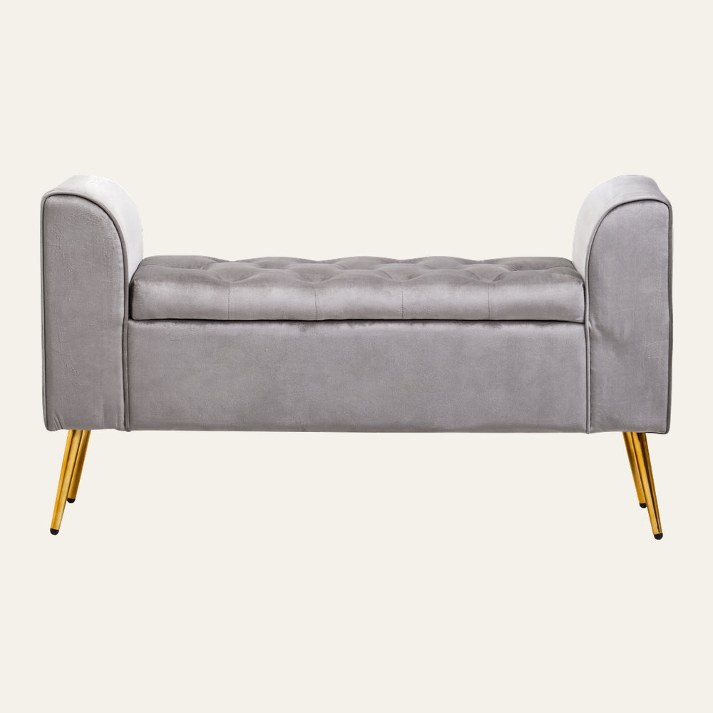 Caelis Velvet Storage Bench in light grey velvet with tufted cushioned top, rolled arms, and angled gold metal legs