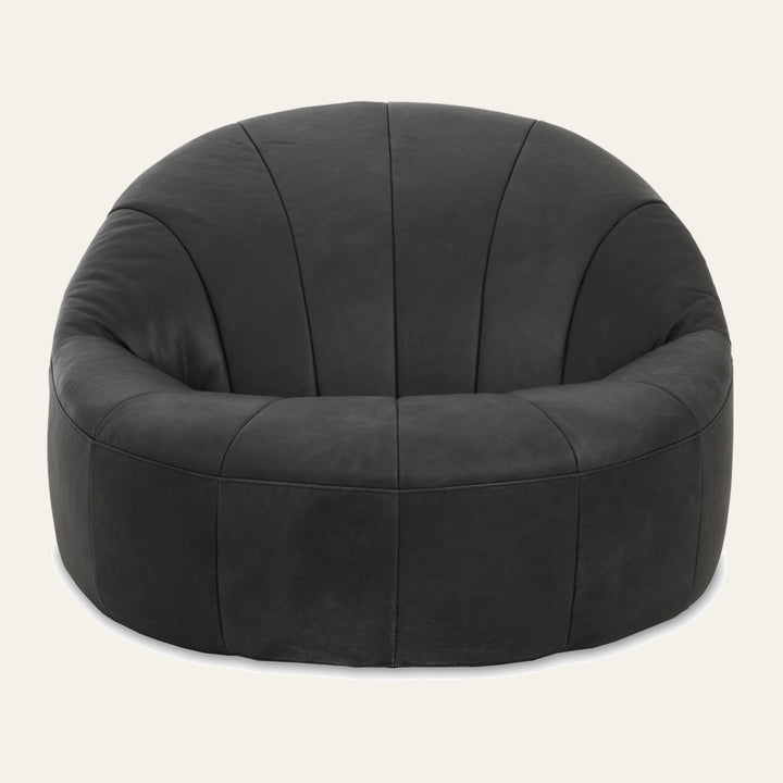 Caelver Accent Chair, low round barrel silhouette in black leather with vertical stitched panels and a deep cushioned seat.