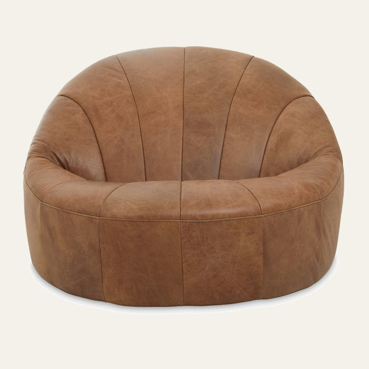 Caelver Chair — low, round lounge chair in warm tan distressed leather with stitched vertical panels and a plush curved back and seat