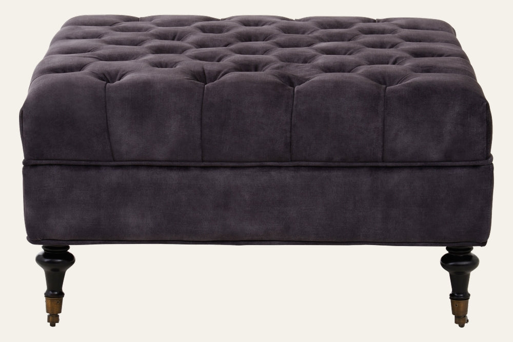 Caia Grey Velvet Ottoman - square tufted grey velvet ottoman with piped edge, turned dark wood legs and brass casters