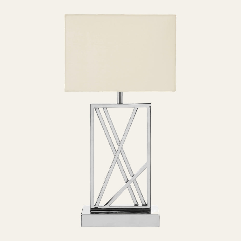 Celesse Metal Table Lamp with rectangular cream fabric shade and open geometric polished chrome metal base featuring diagonal crisscross bars on a rectangular chrome platform.