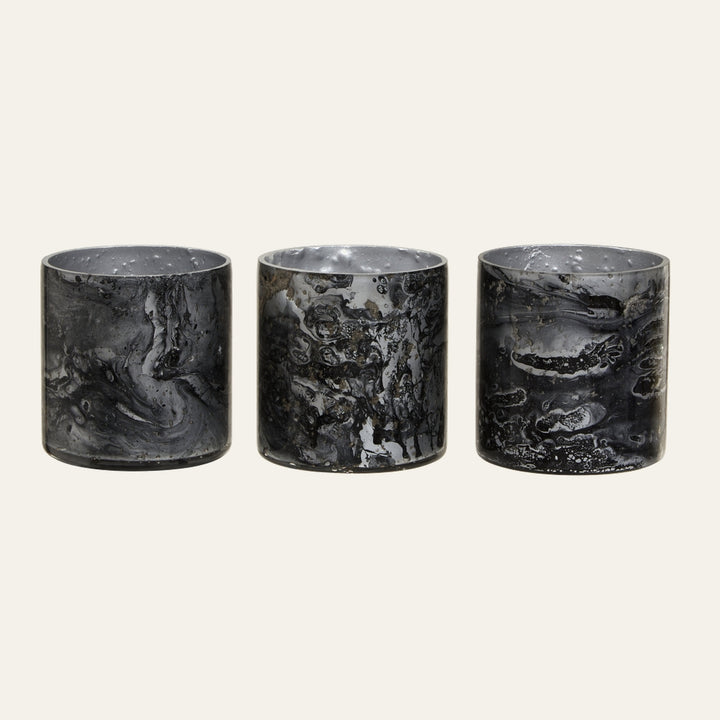 Celthea Marble Glass Tealight Holder Set: three cylindrical black-and-gray marbled glass tealight holders with glossy finish arranged side by side.