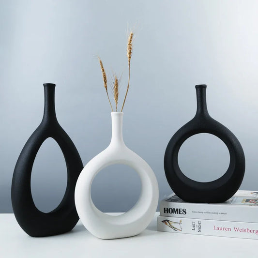 Three decorative vases on a surface with a book titled 'Homes' in the background.
