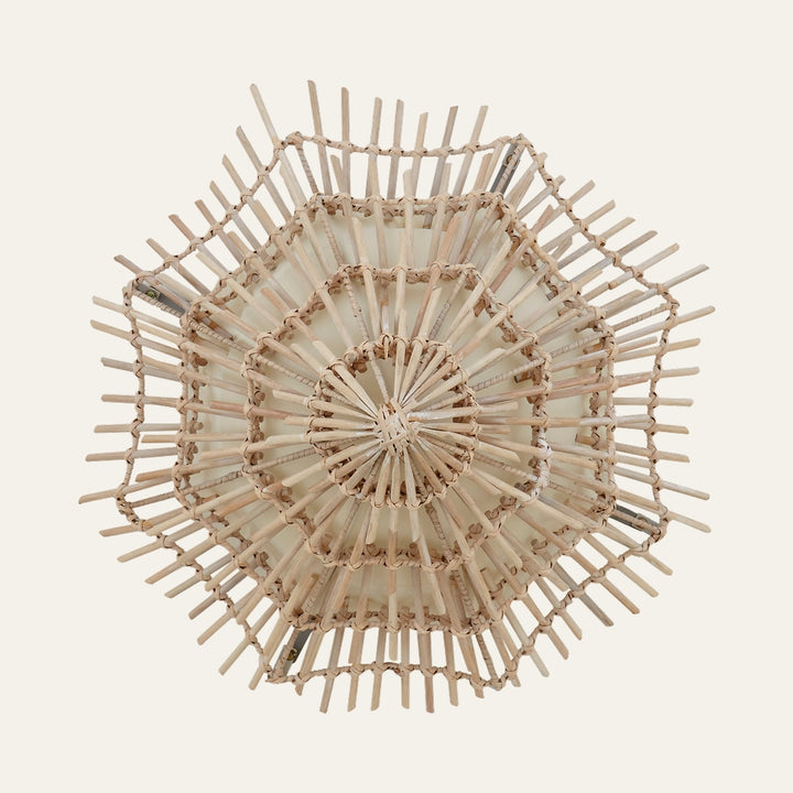 Corric Woven Rattan Wall Light — overhead view of natural woven rattan with layered hexagonal starburst frame and cream inner shade