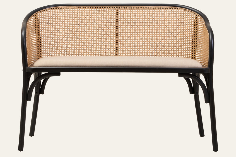 Drevan Cane Wood Bench with rounded black wood frame, natural woven cane backrest and beige upholstered seat cushion on slim black legs.