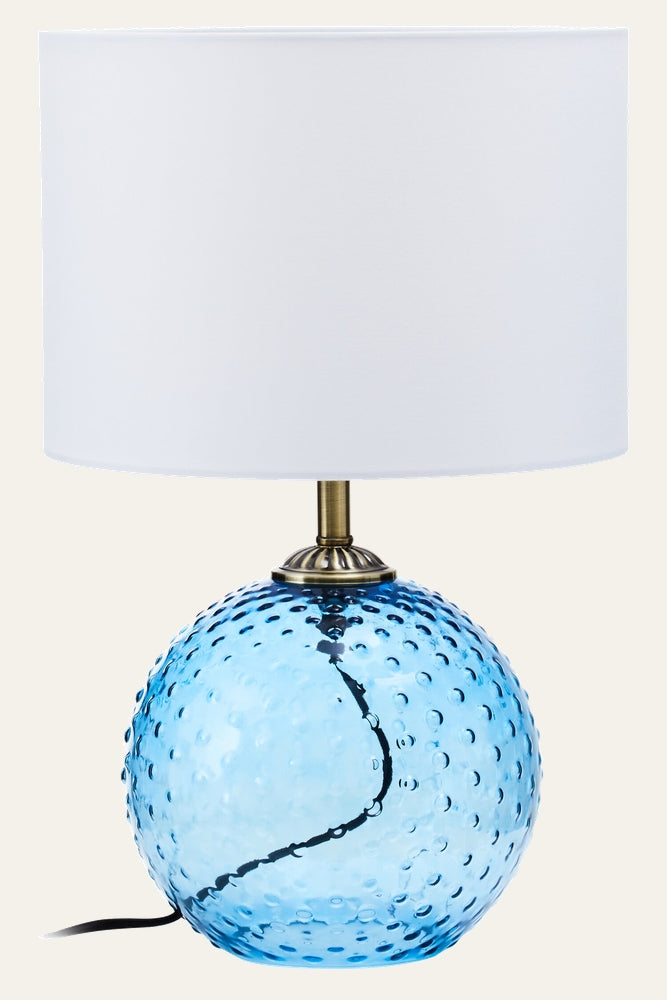 Elivella Table Lamp with blue dimpled glass globe base, brass-finish metal neck, white drum fabric shade and visible black power cord