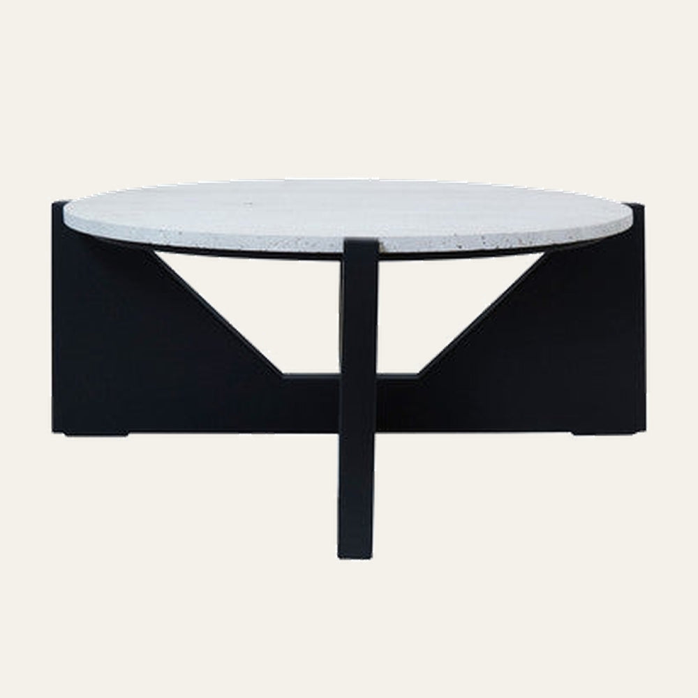 Elsen Travertine Coffee Table with round light travertine top and low black geometric base featuring triangular cutouts and central support