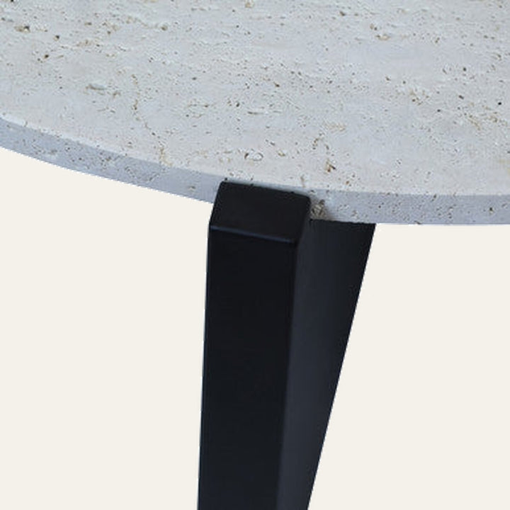Elsen Travertine Coffee Table close-up of round light travertine top with natural pitting and a matte black tapered metal leg