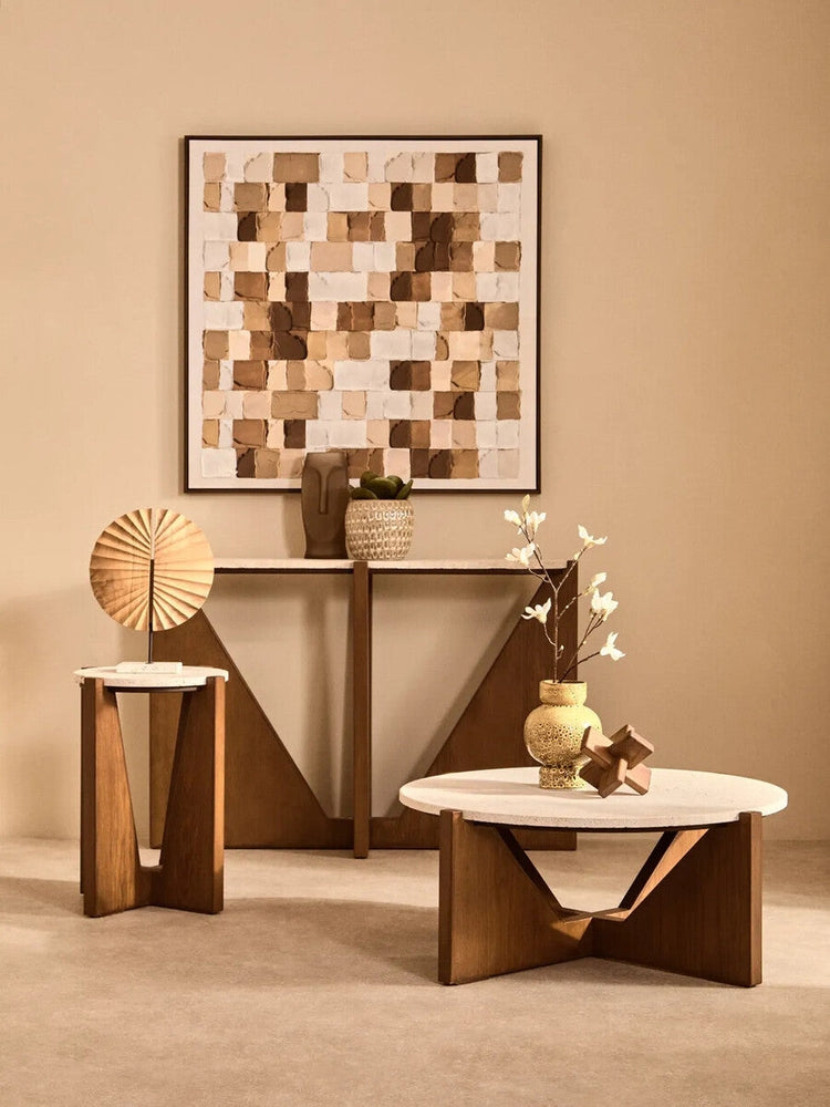 Elsen Travertine Side Table — small round travertine top on a geometric warm wood V-shaped base, styled in a neutral living room with matching coffee table, console and decorative vases.