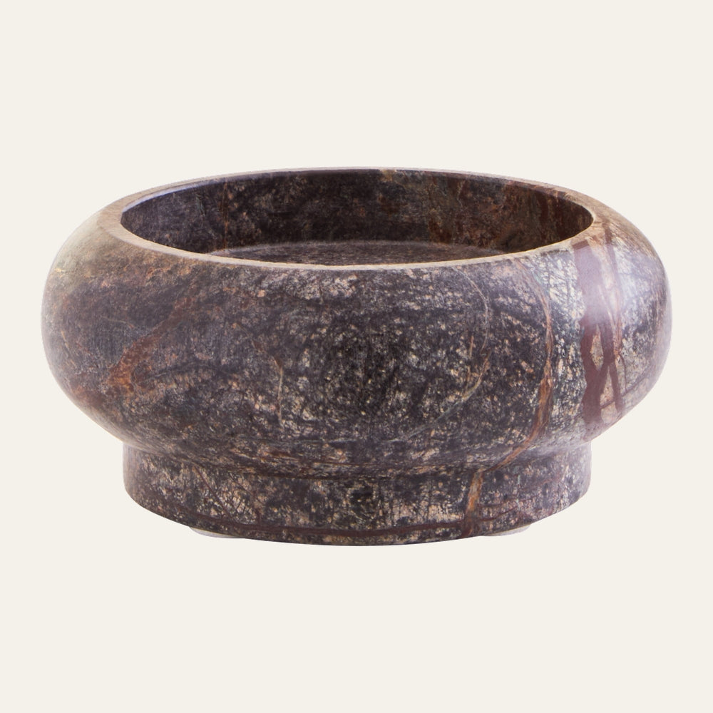 Elys Marble Pillar Candle Holder, round low bowl with short pedestal base in dark mottled marble with reddish and cream veining, polished finish