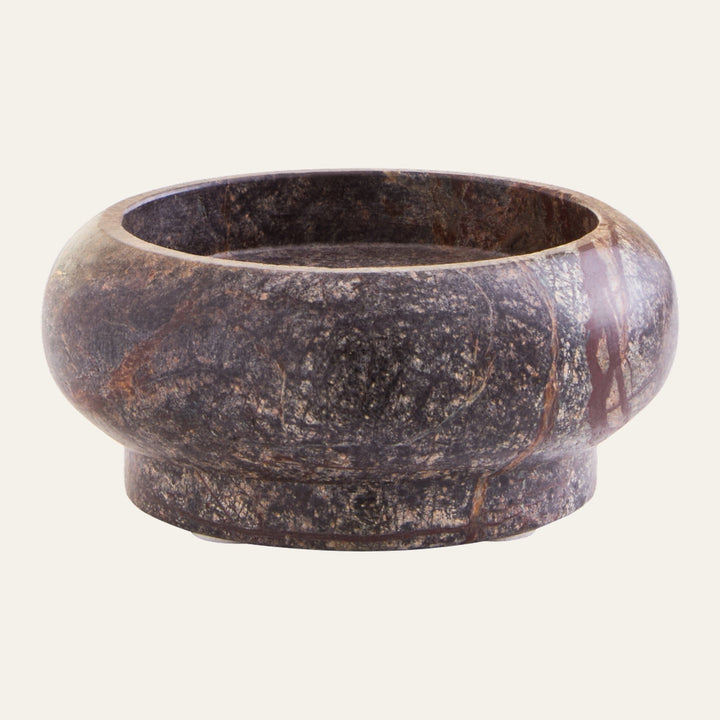 Elys Marble Pillar Candle Holder, round low bowl with short pedestal base in dark mottled marble with reddish and cream veining, polished finish