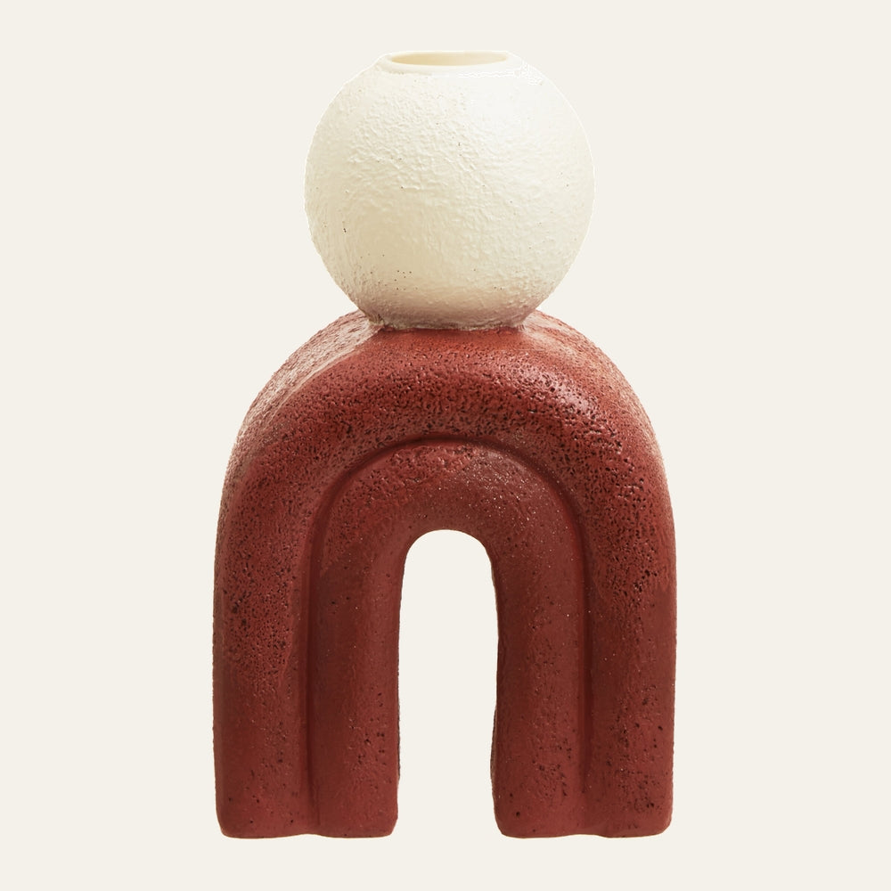 Eriya Candle Holder with textured matte rust-red arch base topped by a textured off-white spherical candle cup