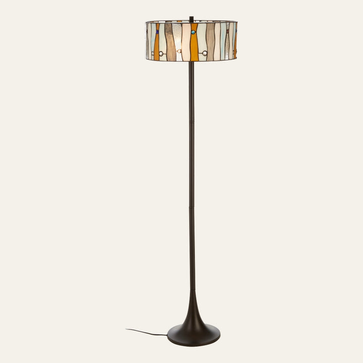 Evaya Floor Lamp with a multicolored stained-glass drum shade of vertical panels and round glass accents, slim dark metal pole and flared round base with visible cord