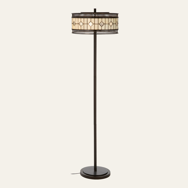 Evaya Floor Lamp with slim dark bronze metal pole and round base, drum stained-glass shade in cream diamond pattern with decorative metal lattice trim