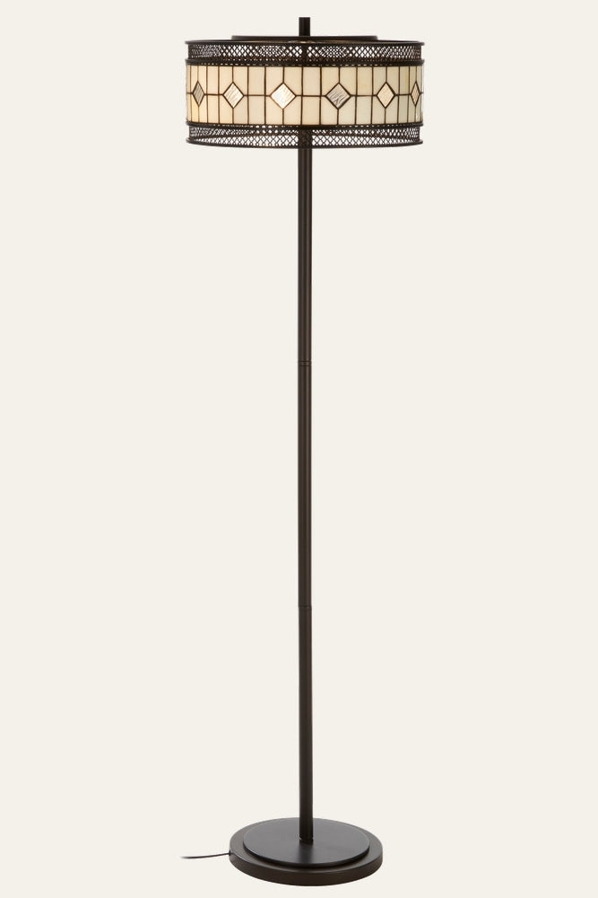 Evaya Floor Lamp with slim dark bronze metal pole and round base, stained-glass drum shade in cream and amber with diamond motif and pierced metal lattice trim