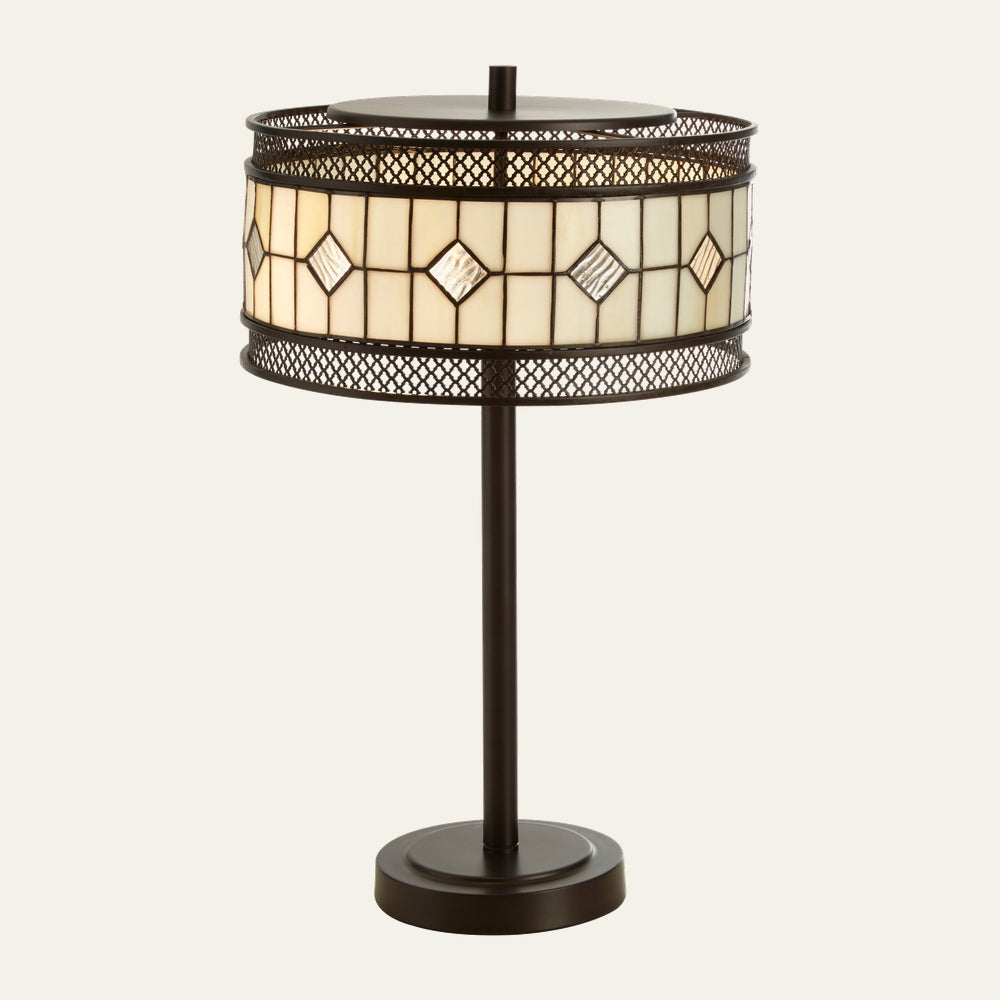 Evaya Table Lamp with dark bronze metal base and straight stem, round stained-glass drum shade with cream panels and textured diamond accents, and decorative mesh metal trim.