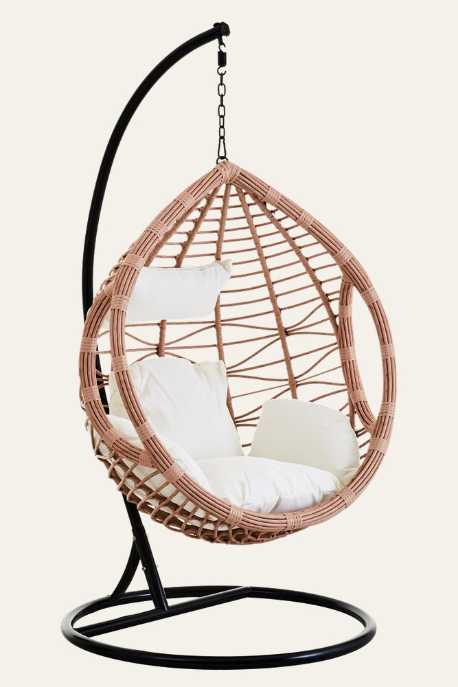 Evira Rattan Effect Hanging Chair — egg-shaped woven rattan-effect frame in soft terracotta with white padded cushions and headrest, suspended from a black metal stand and chain