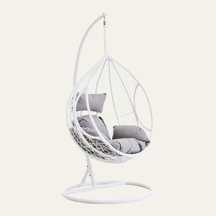Evira White Rattan Grey Hanging Chair: white woven rattan egg seat with plush grey cushions, suspended by chain from a white metal stand