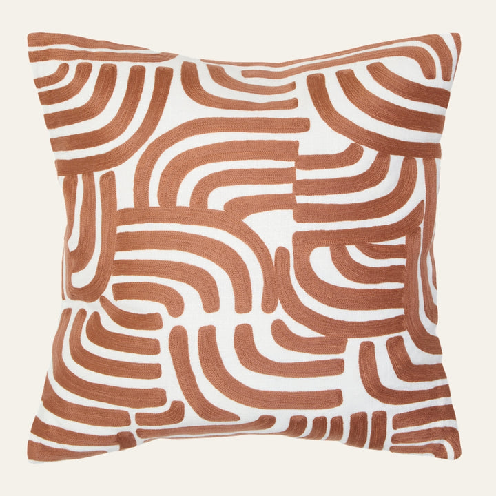 Ezelle Cushion — square white throw pillow with rust‑orange raised embroidered abstract curved-arch pattern