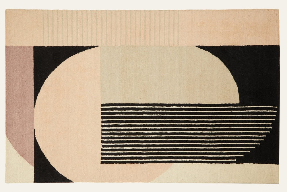 Ezelle Geometric Fabric Rug with abstract geometric pattern featuring large cream and blush semicircles, black blocks and thin horizontal black-and-cream stripes on a fabric surface.
