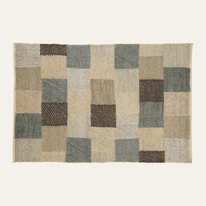 Ezelle Grid Design Rug — rectangular textured woven rug with a patchwork grid of squares in beige, tan, taupe, gray-blue and dark brown