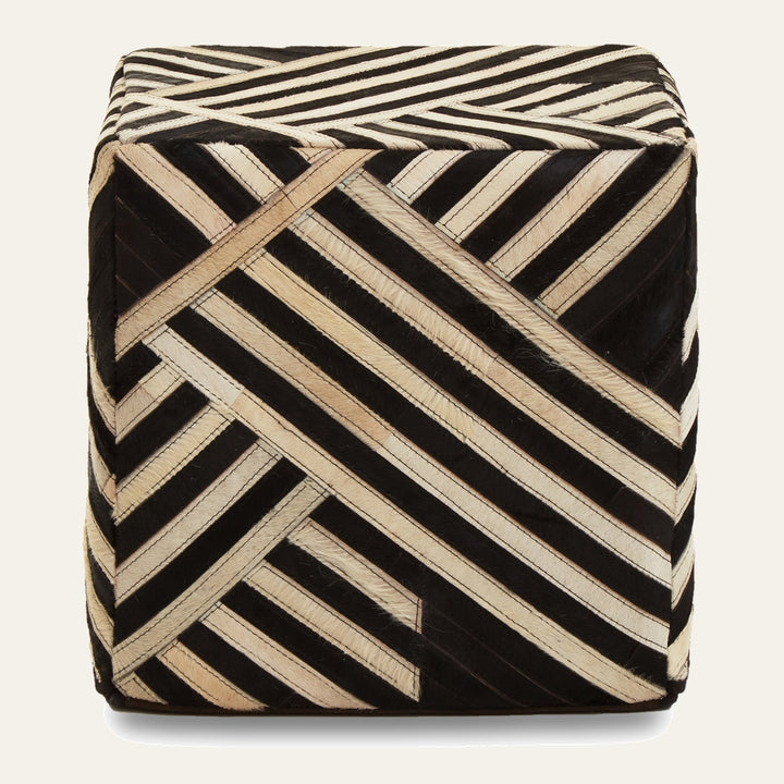 Ezelle Striped Leather Pouffe — cube pouf covered in black and natural hair-on leather strips arranged in a diagonal geometric stripe pattern.