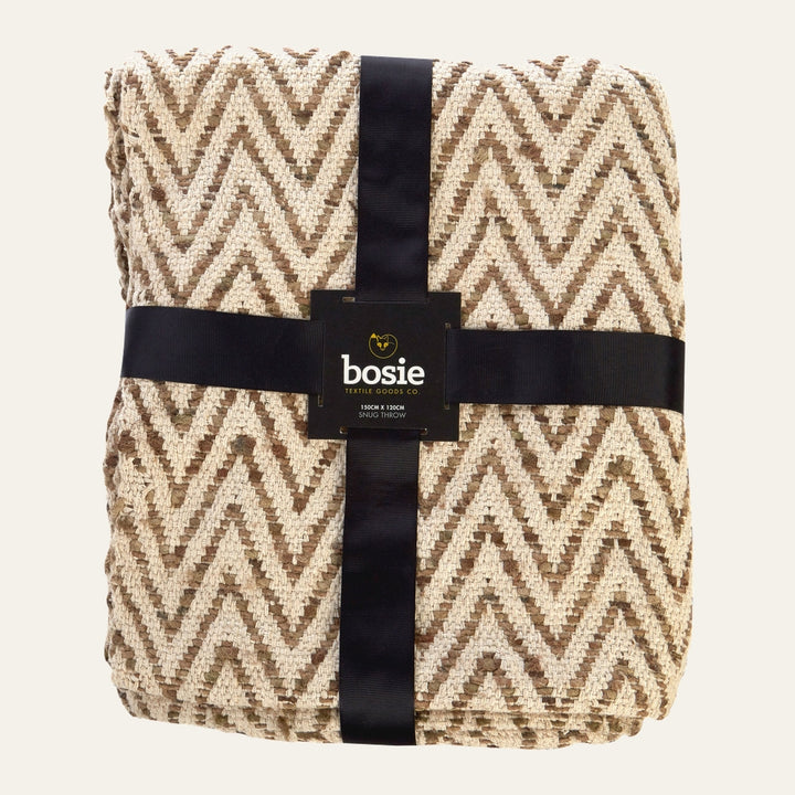 Ezelle Throw — folded textured woven throw with cream and brown chevron zigzag pattern, wrapped with a black ribbon and label