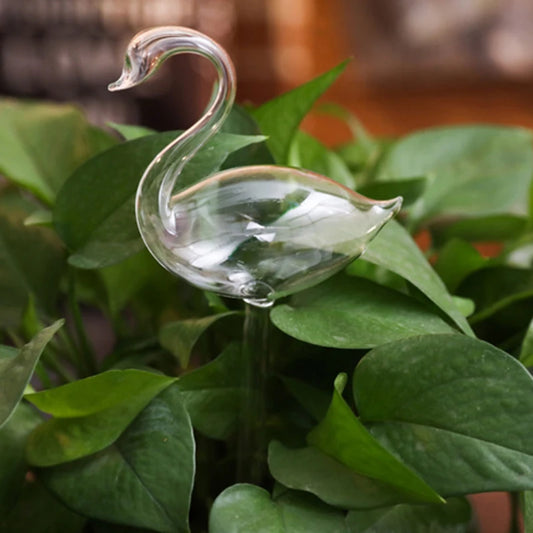 Glass swan-shaped object on a leafy green plant