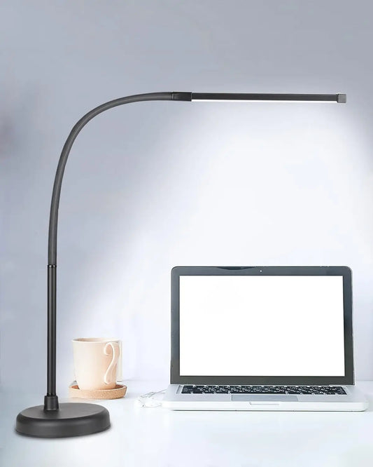 Black adjustable desk lamp next to a laptop on a light gray background