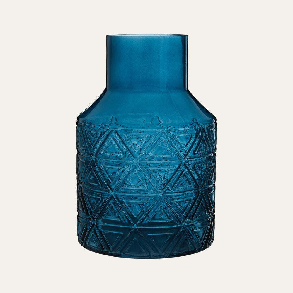 Maelis Blue Glass Vase, deep translucent blue glass with a straight cylindrical neck and textured embossed triangular geometric pattern on the rounded body.