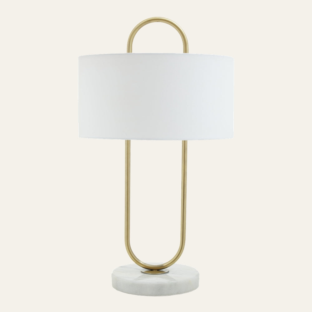 Mavie Fabric Shade Table Lamp with white fabric drum shade, brushed brass U-shaped frame with top loop handle, and round white marble base.