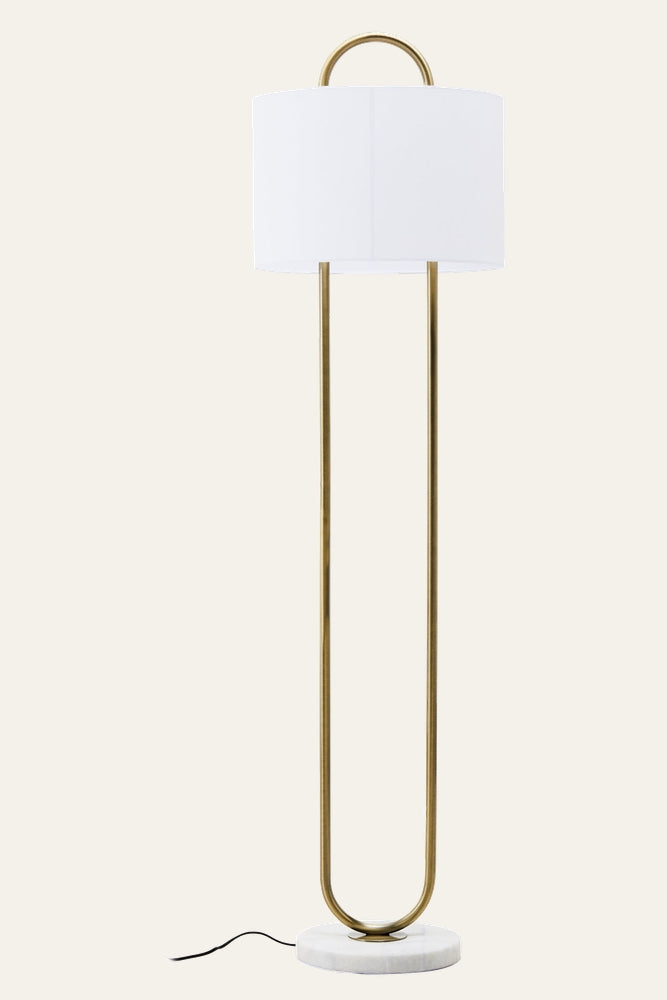 Mavie Gold Floor Lamp — white drum shade atop a gold U-shaped metal frame with arched top, round white marble base and visible black cord.