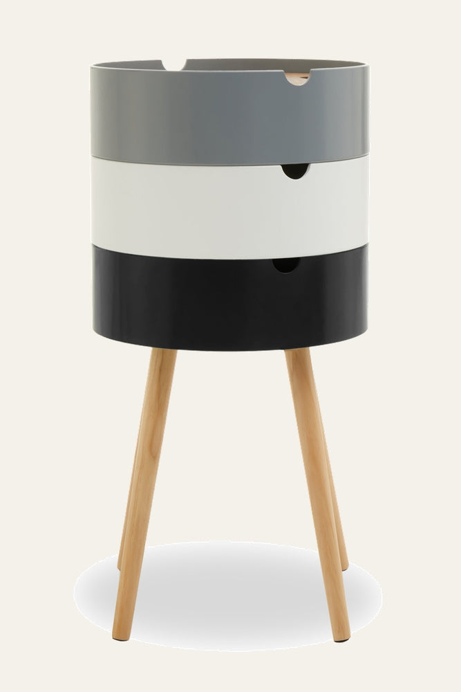 Mirel Three Tier Side Table with stacked gray, white, and black cylindrical compartments with cutout handles and smooth painted finish, supported by three natural tapered wood legs
