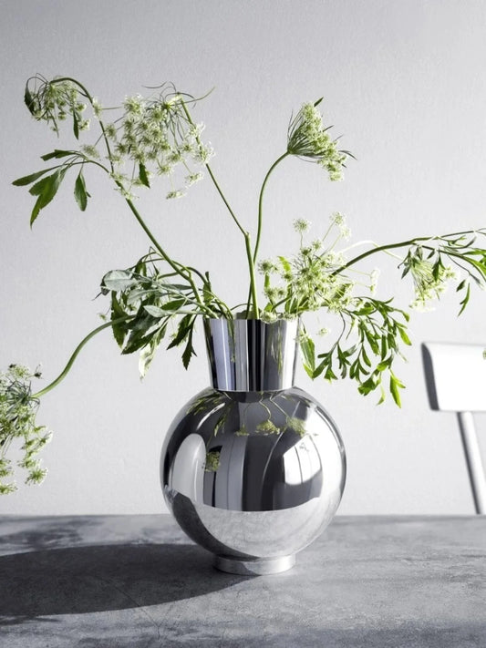 Silver vase with greenery on a light gray surface and background