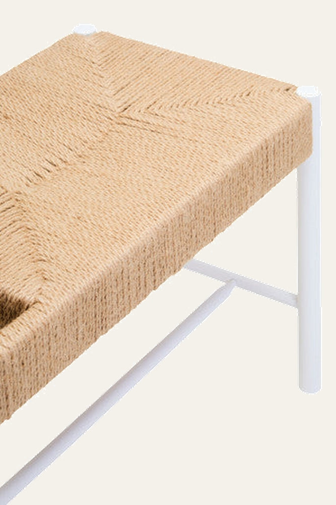 Quildor Open Frame Bench close-up of woven natural fiber seat with chevron weave and white metal open-frame legs with crossbar.