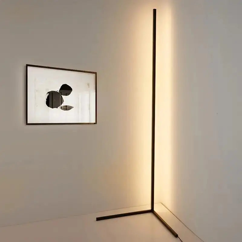 Modern floor lamp casting a long shadow on a wall with a framed abstract artwork.